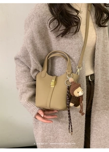 Détail du sac seau camel avec fermoir doré et charm ours sur un modèle minimaliste