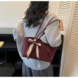 Détail du cabas bordeaux avec texture tressée, poignée nouée et foulard en soie décoratif