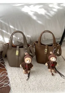 Détail de sacs seaux en cuir grainé avec fermoirs dorés et pendentifs ours en peluche