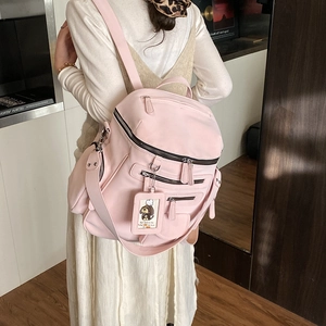 Detailed view of pale pink nylon travel backpack with multiple zippered compartments and card tag