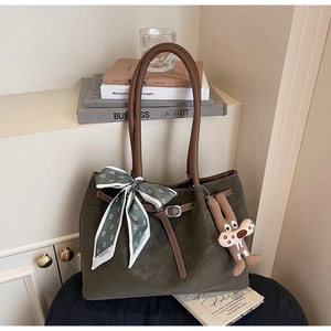 Detail of olive suede tote bag with floral silk scarf and brown leather handles