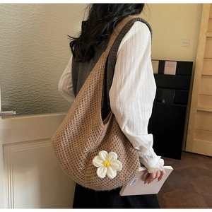 Detailed side view of large crochet straw tote bag with white flower charm accessory