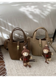 Détail de sacs seaux en cuir marron et kaki avec de mignons charms en forme d'ours