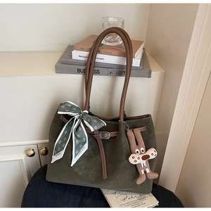 Detail of retro olive green tote bag with silk scarf and cute doll pendant accessory