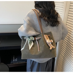 Olive green suede tote bag with floral scarf and plush charm shown on person