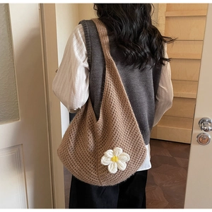 Detail of a brown chunky knit tote bag featuring a white daisy crochet flower applique