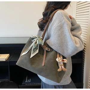 Detail of olive green suede tote bag with brown leather handles and floral scarf