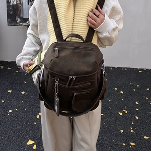 Close-up of a dark brown suede backpack with vintage multi-zipper pocket details