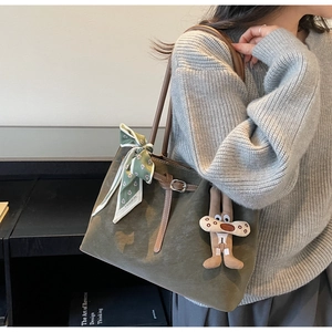 Detail of suede tote bag with floral scarf and cute plush pendant charm on shoulder strap