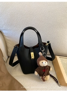 Détail du sac seau en cuir grainé noir avec fermoir doré et charm d'ours en peluche