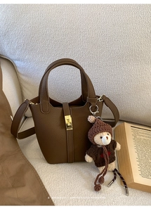 Détails d'un sac seau en cuir marron avec breloque ours en peluche et fermoir doré chic