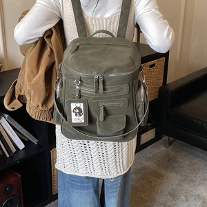 Detail of army green canvas backpack with multiple pockets and decorative cartoon tag