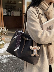 Large dark brown suede tote bag with floral scarf and bunny charm in winter street setting