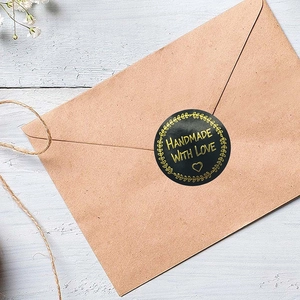 Black and gold round Handmade with Love stickers for packaging on a kraft envelope