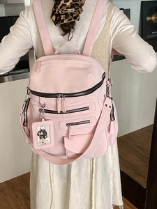 Pink multi-pocket nylon backpack for travel with detachable strap shown on a model