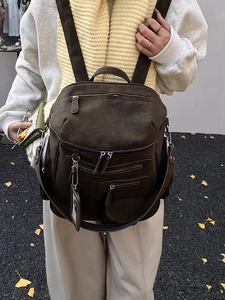 Deep brown matte leather travel backpack with multi-pocket design shown on model