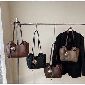 Detail view of four leather tote bags in brown, black, and khaki with rope handles