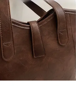 Close-up of vintage brown tote bag stitching details and buckle closure texture