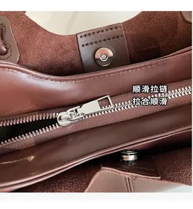 Detail view of smooth silver zipper and magnetic clasp on dark brown leather tote bag