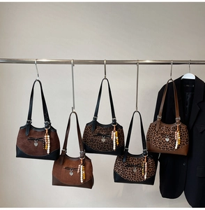 Close-up of retro leopard print suede bags with heart charms and bow tassel details