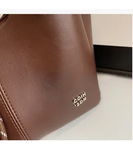 Detailed macro view of dark brown lychee texture leather with silver metal logo logo