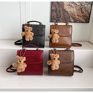 Detail of four retro PU leather backpacks in black, brown and burgundy with bear charms