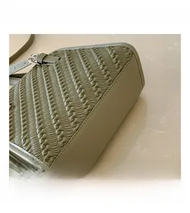 Detalle de la textura tejida y la hebilla de metal plateado en el bolso de hombro gris-verde