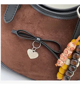 Detail of brown suede tote with heart pendant and colorful wooden bead charms