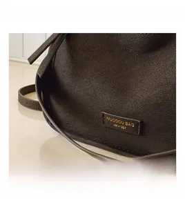 Close-up of vintage textured leather with golden logo label on a brown crossbody bag
