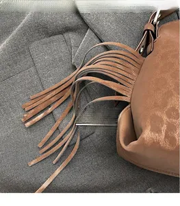 Détail d'un sac à main en daim marron avec de longues franges et des boucles métalliques