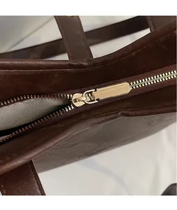 Macro detail of high-quality gold zipper hardware on premium brown leather tote bag
