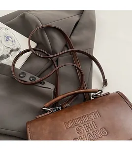 Detail of brown PU leather bag with embossed texture and sleek silver hardware on blazer