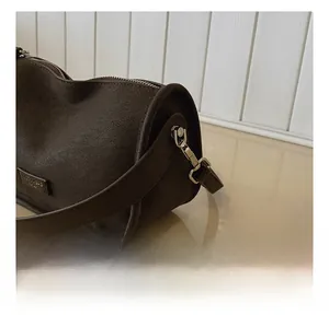 Close-up of silver metal swivel hook and brown lychee grain leather strap on a pillow bag