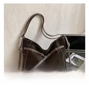 Macro shot of brown tote bag featuring white contrast stitching and silver metal buckles