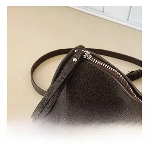 Close-up detail of smooth metal zipper and lychee textured brown leather handbag