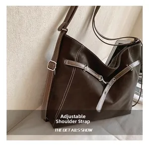 Detail view of adjustable strap with white contrast stitching on vintage brown bag