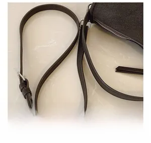 Detail view of dark brown litchi leather texture with adjustable silver buckle strap