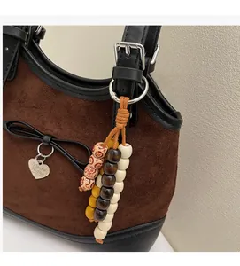 Detail of brown suede tote bag with black leather trim and heart charm pendant