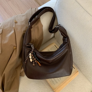 Close-up of brown litchi pattern leather bag with colorful wooden bead tassel charm