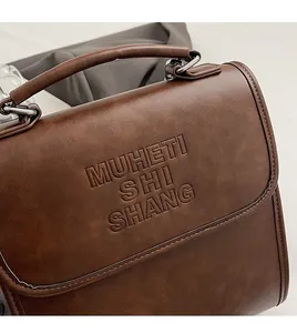 Detail of vintage brown faux leather backpack featuring embossed lettering and lychee texture