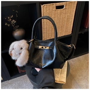 Détail du sac dumpling noir plissé avec boucle dorée et accessoire de lapin mignon
