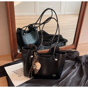 Detail of black tote bag with plush charm reflected in a wooden frame mirror