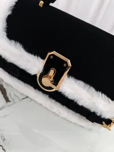 Dettaglio della borsa nera opaca con bordo in finta pelliccia bianca e chiusura in oro