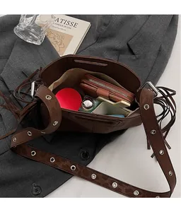 Détail du grand sac en daim marron foncé avec franges et œillets métalliques argentés