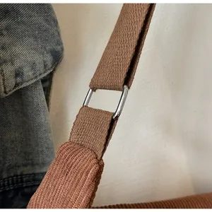 Detail of corduroy shoulder strap with polished silver metal buckle on brown tote bag