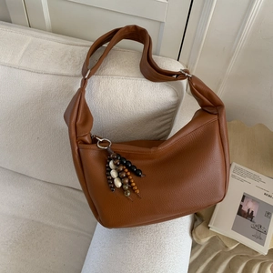 Detailed view of caramel leather bag texture with vintage wooden bead zipper pull decoration