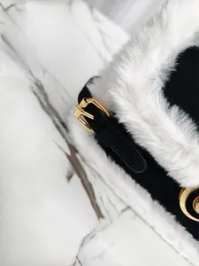 Dettaglio borsa in pelle nera con bordo in ecopelliccia bianca e fibbia dorata