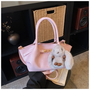Sac à main plissé rose avec pendentif lapin en peluche sur une étagère déco noire