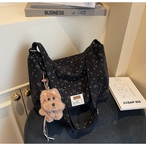 Détail d'un sac cabas en velours côtelé noir avec motifs cœurs et breloque chiot rose