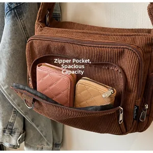 Detail view of brown corduroy crossbody bag with multiple zippers and spacious interior
